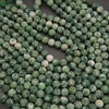 Close-up of green and white marbled beads on a dark background