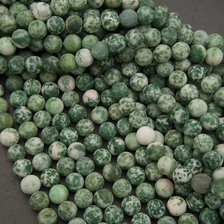 Close-up of green and white marbled beads on a dark surface