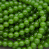 A close-up pile of glossy, round green beads with a smooth, polished surface.