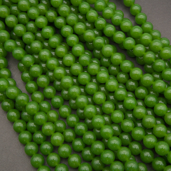 Green round gemstone beads arranged in overlapping strands on a dark gray background.