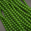 Green round gemstone beads arranged in overlapping strands on a dark gray background.
