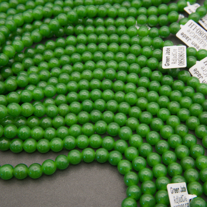 Strands of smooth round green jade large hole beads laid out with Tejas Beads tags