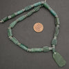 Green glass beads necklace with a penny for scale on a gray background