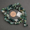 String of green and white gemstones with a penny for scale on a gray background