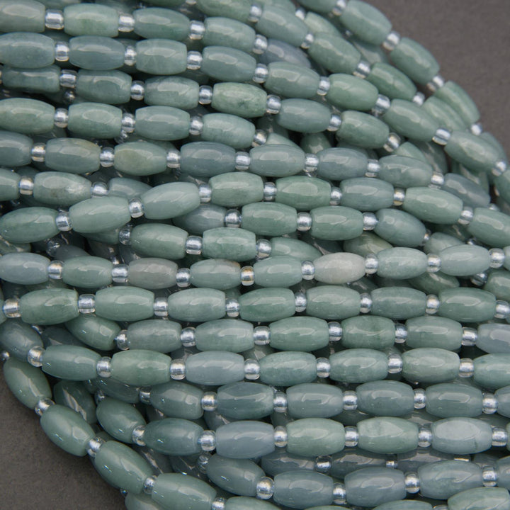 Close-up of a string of green beads with silver spacers on a gray background
