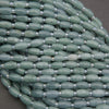 Close-up of a string of green beads with silver spacers on a gray background