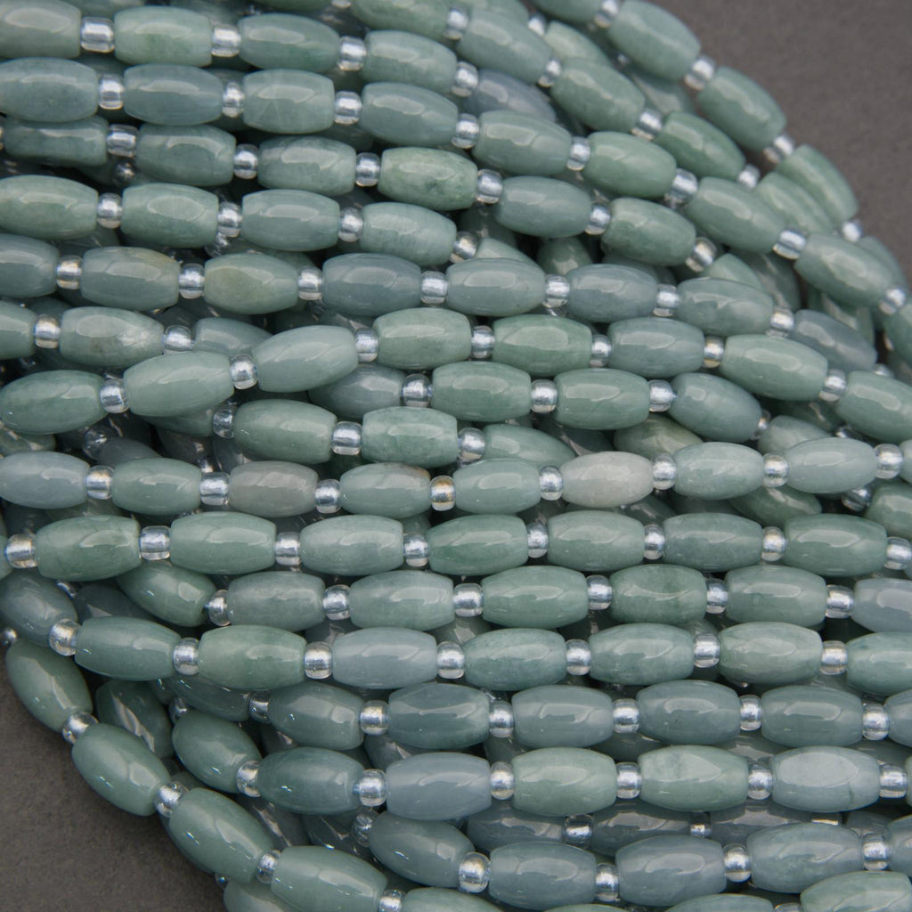 Close-up of a string of green beads with silver spacers on a gray background