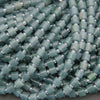 Close-up of green beads with silver accents on a gray background
