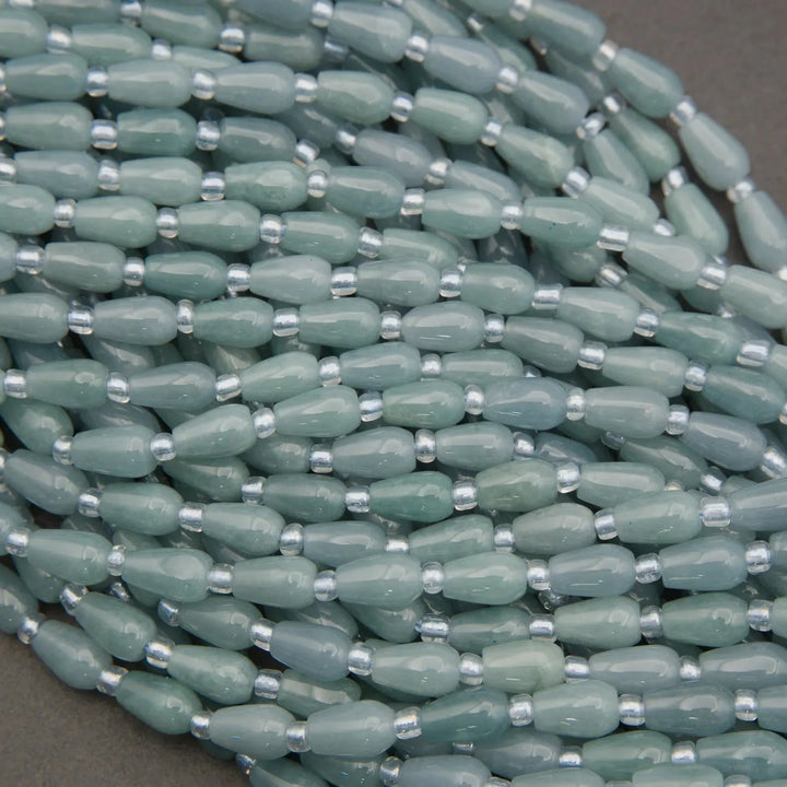 Close-up of a string of light green beads with silver accents on a dark background