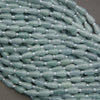 Close-up of a string of light green beads with silver accents on a dark background