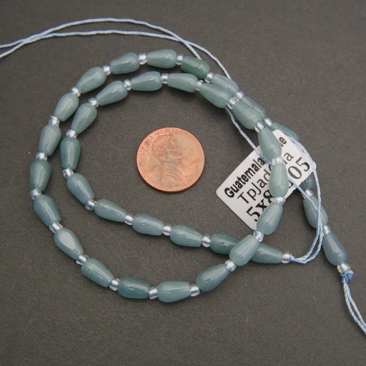 String of light blue beads with a penny and label for size on a gray background