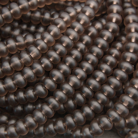 A close-up of many small, smooth, dark brown translucent beads arranged in overlapping rows.