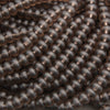 A close-up of many small, smooth, dark brown translucent beads arranged in overlapping rows.