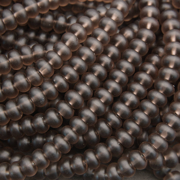 A close-up of many small, smooth, dark brown translucent beads arranged in overlapping rows.