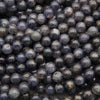 Polished iolite round beads featuring deep indigo, smoky violet, and natural gray mineral inclusions.