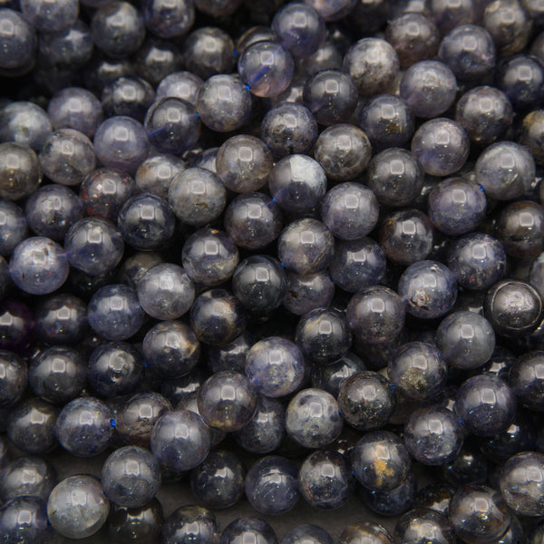 Polished iolite round beads featuring deep indigo, smoky violet, and natural gray mineral inclusions.
