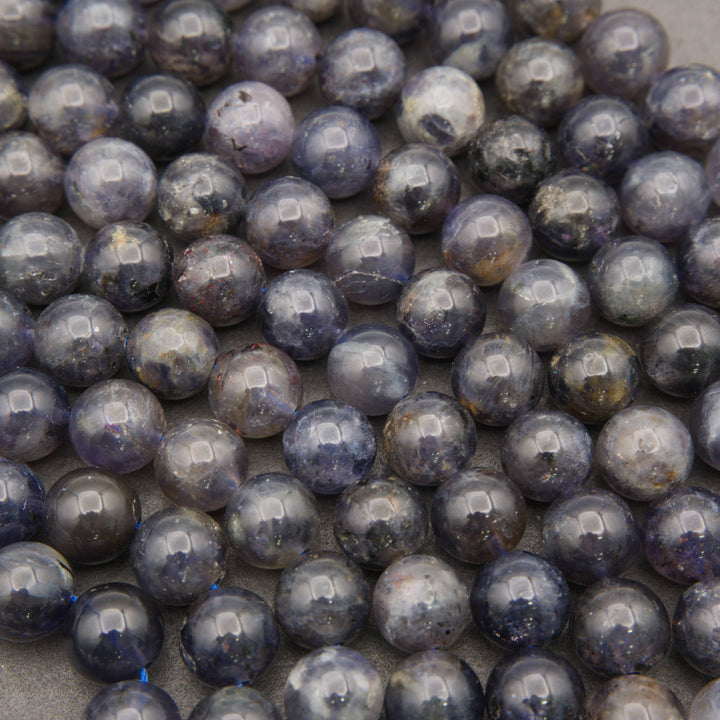 Natural iolite gemstone beads displaying rich blue-purple tones and subtle cloudy patterns.