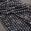 Iolite gemstone round beads displaying deep bluish-purple coloration with earthy gray and brown inclusions.
