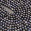 Polished iolite round beads featuring deep indigo, smoky violet, and natural gray mineral inclusions.