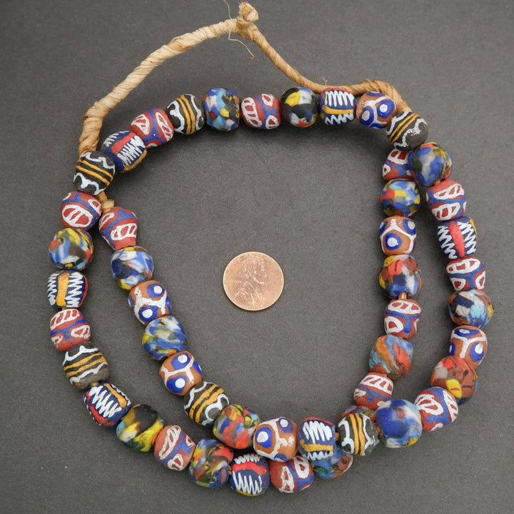 Colorful bead necklace on a dark background with a penny for scale