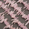 Pink stone chips or beads arranged in loose curved lines on a dark gray textured background.