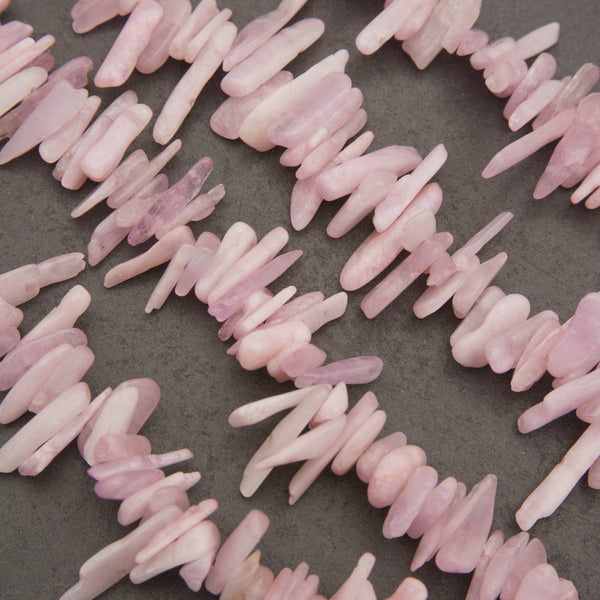 Pink stone chips or beads arranged in loose curved lines on a dark gray textured background.