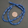 String of blue beads with a penny for scale on a gray background