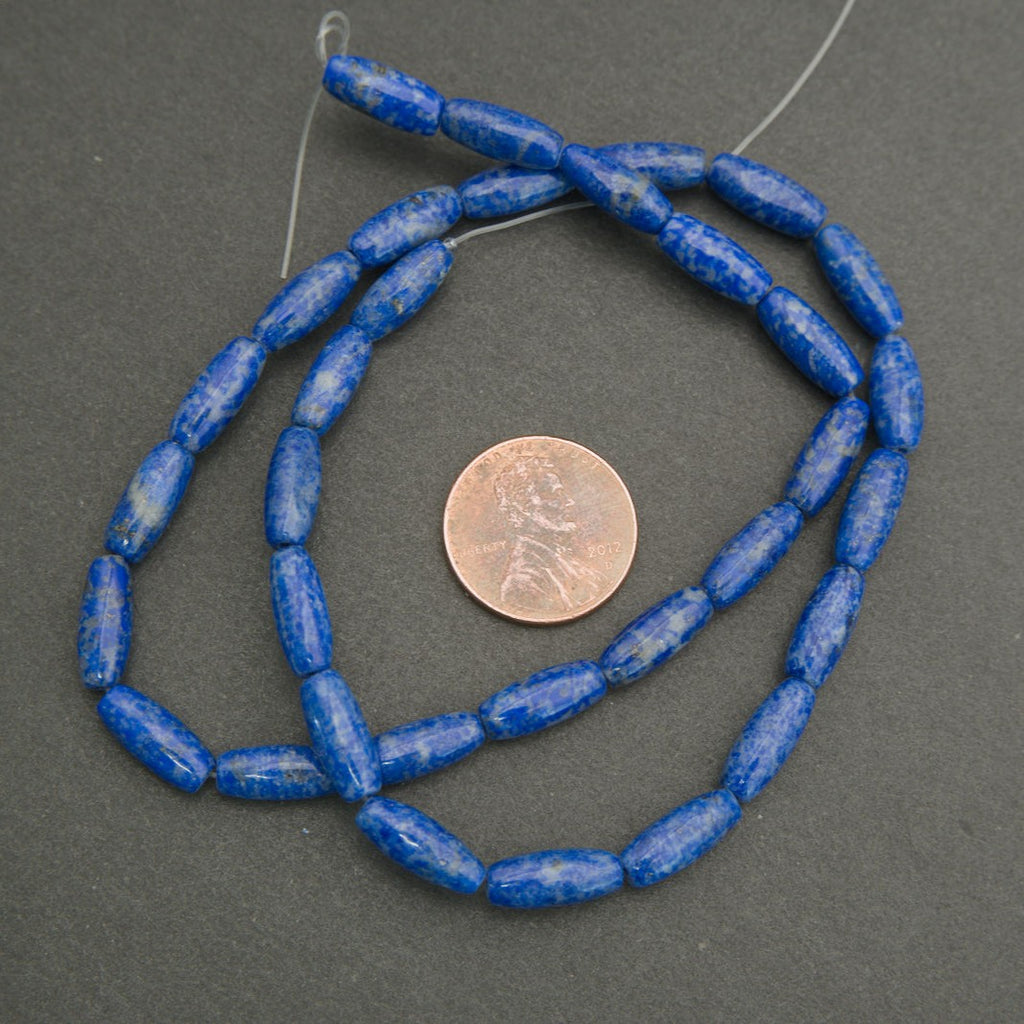 String of blue beads with a penny for scale on a gray background