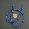 Blue bead necklace with a penny for scale on a gray background