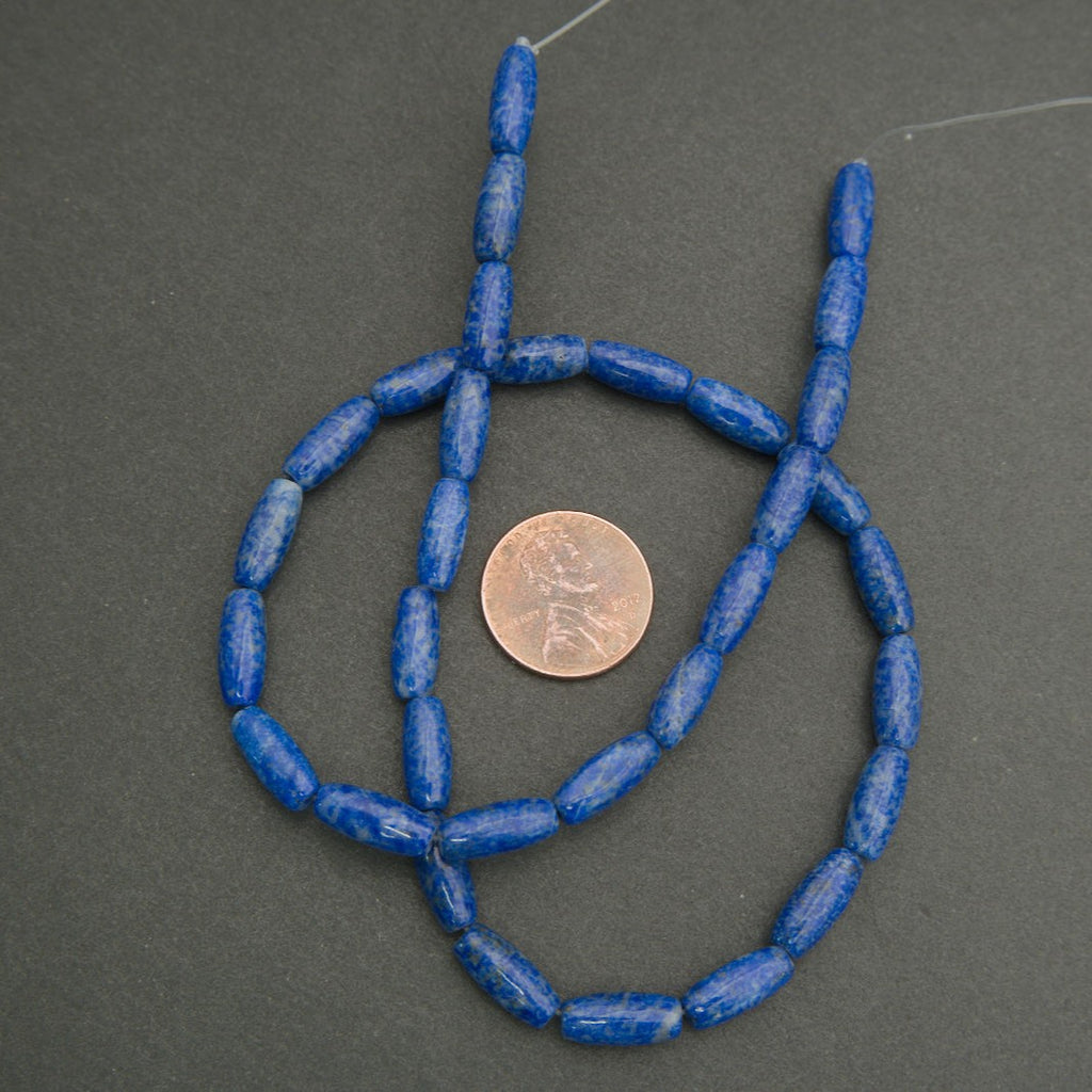 Blue bead necklace with a penny for scale on a gray background