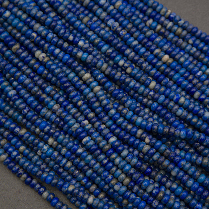 Close-up of blue lapis lazuli gemstone rondelle beads with natural mineral patterns and a soft matte finish.