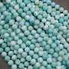A heap of smooth round larimar bead strands in vivid turquoise blue with white turtleback patterns