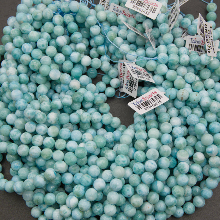 A bundle of smooth round larimar bead strands with Tejas Beads tags