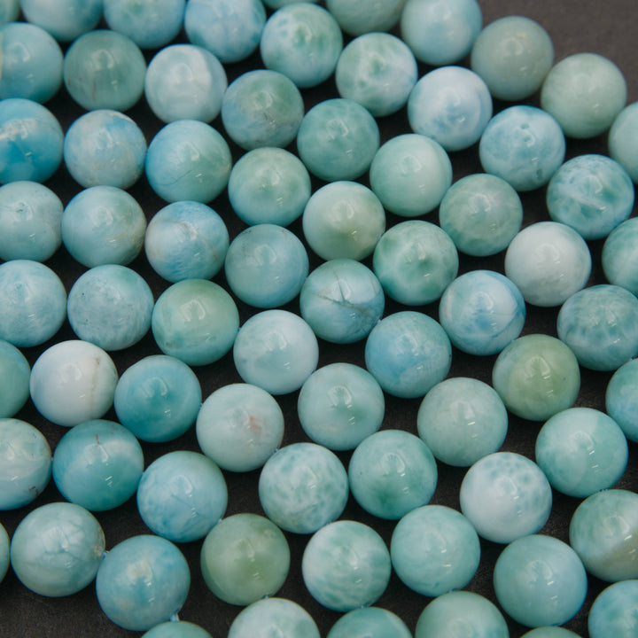 Close-up of smooth round larimar beads showing turquoise blue, sea green and white turtleback patterns