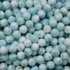 Smooth round larimar beads in pale sky blue and light aqua with white cloudy patterns