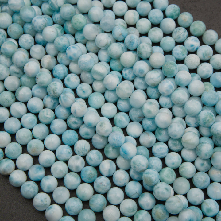 A heap of smooth round larimar bead strands in pale sky blue with white patterns
