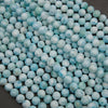 A heap of smooth round larimar bead strands in pale sky blue with white patterns