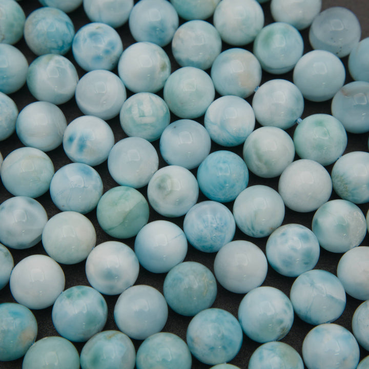 Close-up of smooth round larimar beads showing pale sky blue and white cloudy patterns