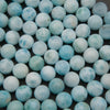 Close-up of smooth round larimar beads showing pale sky blue and white cloudy patterns