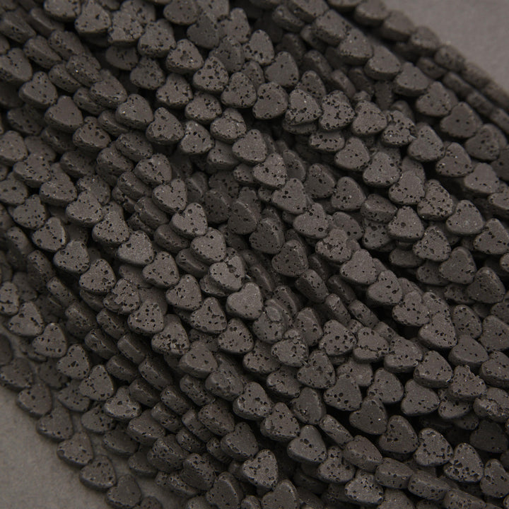 Close-up of matte black lava rock heart beads featuring natural pitting and distinctive surface textures.