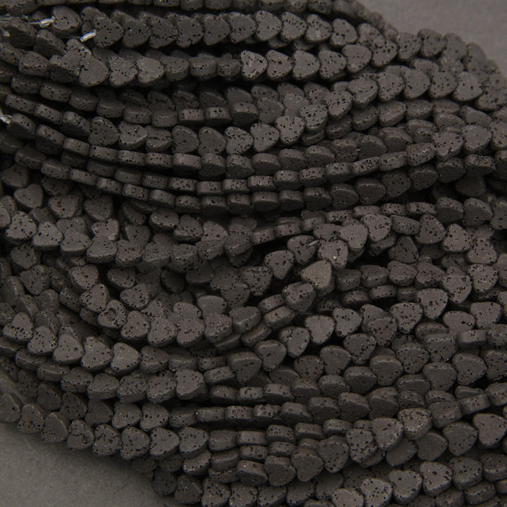 Strands of black volcanic lava stone heart-shaped beads with a textured charcoal-black finish.