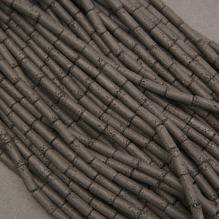 Close-up of black lava rock cylindrical beads showcasing natural pitting and a charcoal-black surface.