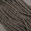 Close-up of black lava rock cylindrical beads showcasing natural pitting and a charcoal-black surface.