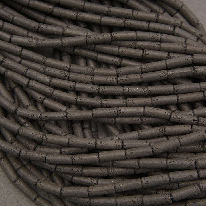 Multiple strands of matte black lava stone tube beads with elongated shapes and natural volcanic pores.