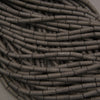 Multiple strands of matte black lava stone tube beads with elongated shapes and natural volcanic pores.