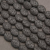 Natural black lava stone oval beads with a matte finish and porous volcanic texture, ideal for jewelry making.