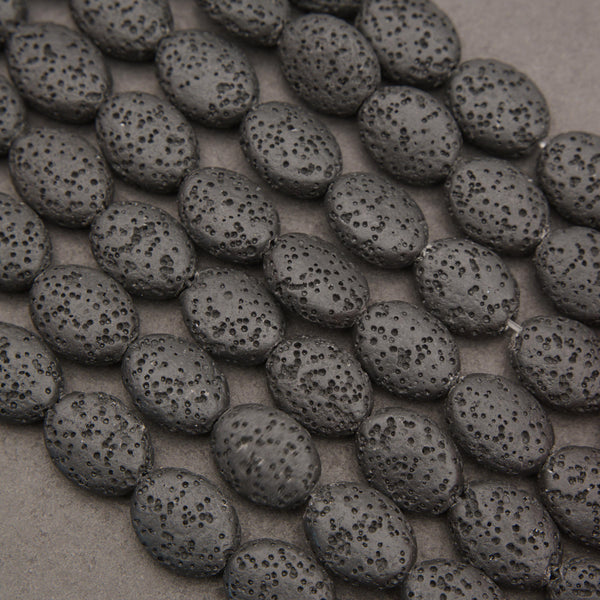 Natural black lava stone oval beads with a matte finish and porous volcanic texture, ideal for jewelry making.