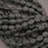 Strands of black volcanic lava stone oval beads with textured surfaces for handmade bracelets and necklaces.