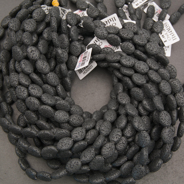 Matte black lava stone oval gemstone beads showcasing natural volcanic pores and unique surface textures.