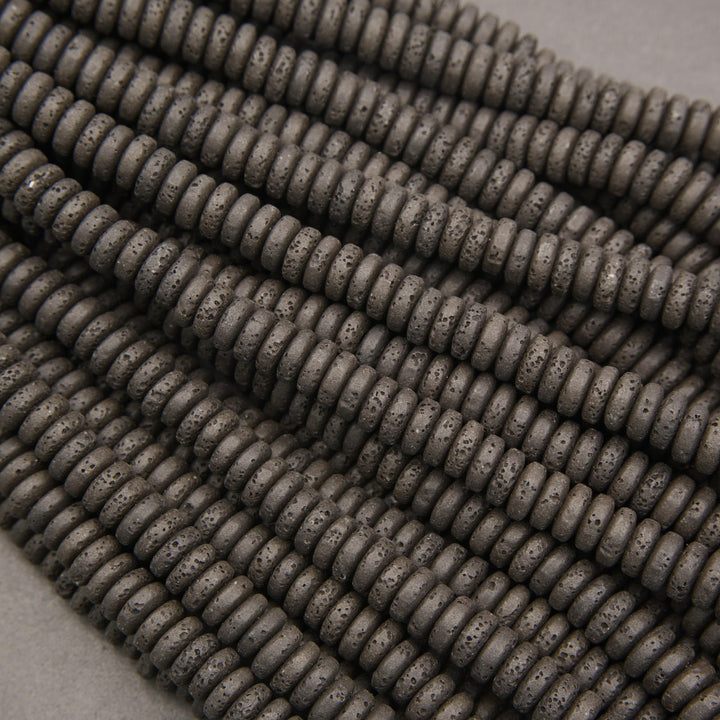 Multiple strands of matte black lava stone disk beads showcasing natural pores and charcoal-black surfaces.